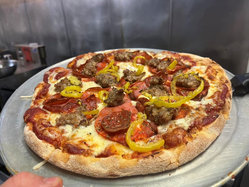 A pizza with pepperoni, banana peppers, and Canadian bacon