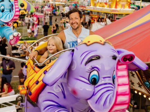 dad and daughter riding a ride at the fair