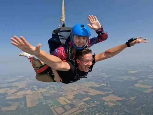 two people skydiving while one person waves 