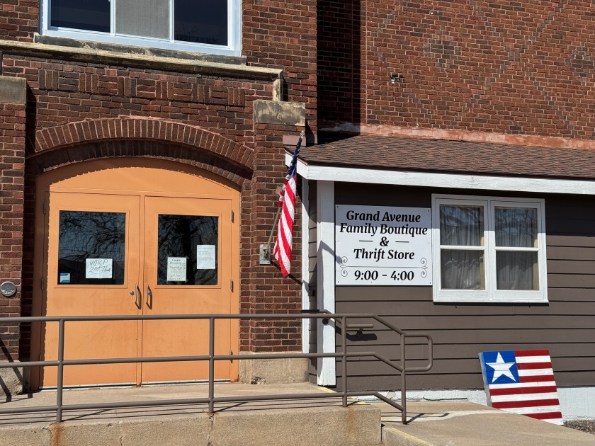 Outside of Grand Avenue Family Boutique with a sign saying they are open from 9am-4pm