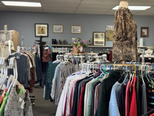 Many racks filled with clothes inside a thrift store